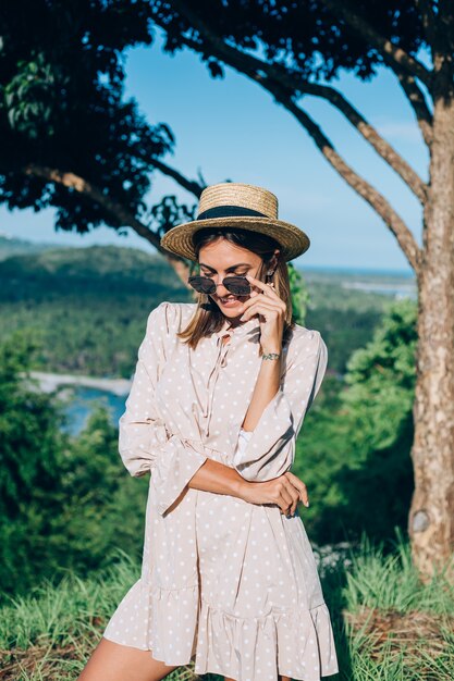 Retrato de jovem feliz com vestido de verão, óculos escuros e chapéu de palha