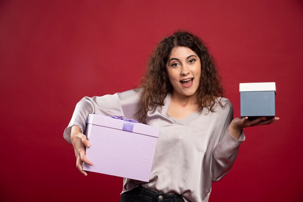 Retrato de jovem feliz segurando caixas de presente.