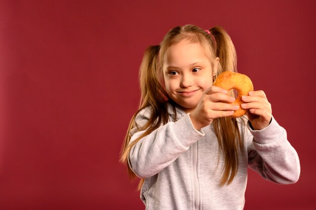 Foto grátis retrato de jovem garota segurando rosquinha saborosa