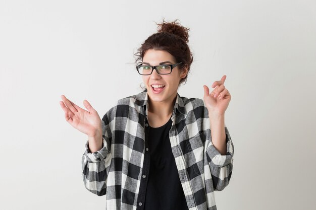 Retrato de jovem hippie sorrindo linda mulher em camisa quadriculada com expressão de carinha engraçada usando óculos posando isolado no fundo branco do estúdio, emocional