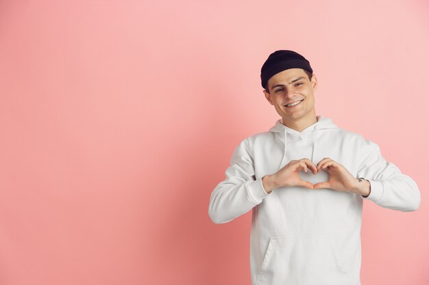 Retrato de jovem homem caucasiano com emoções brilhantes sobre fundo rosa studio