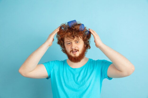 Retrato de jovem homem caucasiano em seu dia de beleza e rotina de cuidados com a pele. Modelo masculino com cabelo ruivo natural fazendo o penteado, precisa de mais cacheado. Cuidado corporal e facial, conceito de beleza masculina natural.