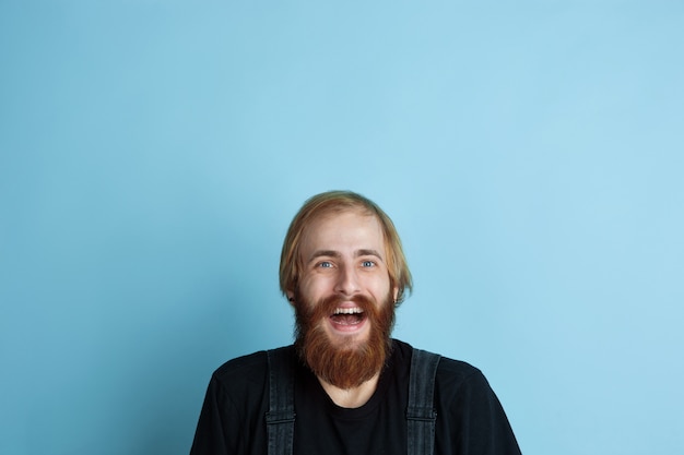 Retrato de jovem homem caucasiano parece sonhador, bonito e feliz. olhando para cima e pensando no espaço azul