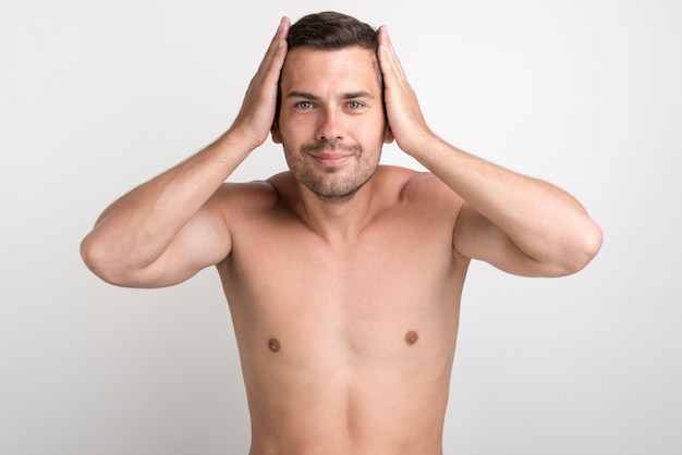 Foto grátis retrato, de, jovem, homem sorridente, tocar, seu, cabelo, olhando câmera, ficar, contra, fundo branco