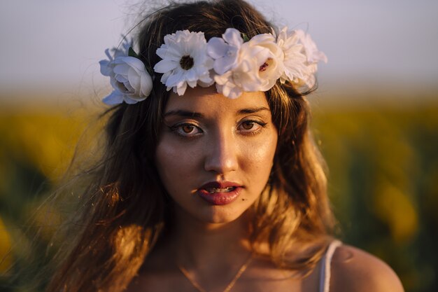 Retrato de jovem morena caucasiana com coroa de flores em foco raso