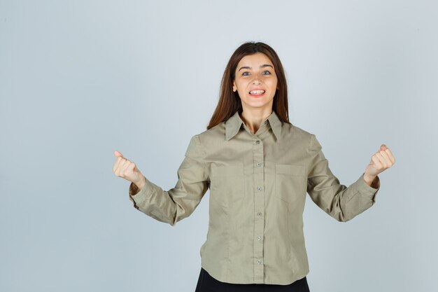 Retrato de jovem mostrando gesto de vencedor com camisa, saia e vista frontal com sorte