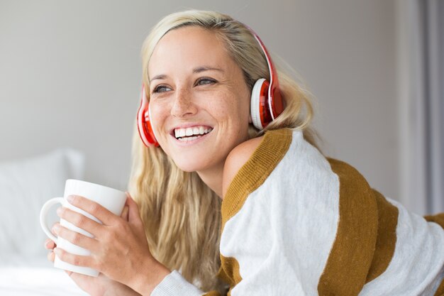 Retrato de jovem mulher em fones de ouvido rindo