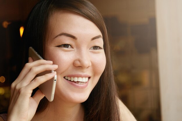 Retrato de jovem mulher morena, usando telefone