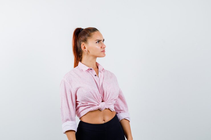 Foto grátis retrato de jovem olhando para cima em uma camisa, calça e olhando pensativa com vista frontal