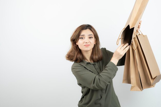 Retrato de jovem segurando sacos de papel artesanal e de pé. Foto de alta qualidade