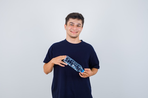 Retrato de jovem segurando uma garrafa de água em uma camiseta preta e olhando a vista frontal alegre