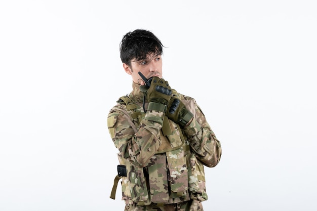 Retrato de jovem soldado em uniforme militar na parede branca