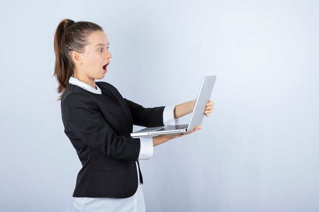 Retrato de jovem usando laptop sobre uma parede branca.