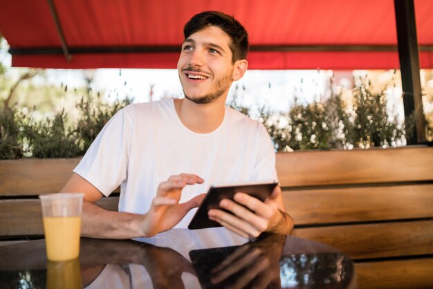 Retrato de jovem usando um tablet digital enquanto está sentado em uma cafeteria. Conceito de tecnologia e estilo de vida.