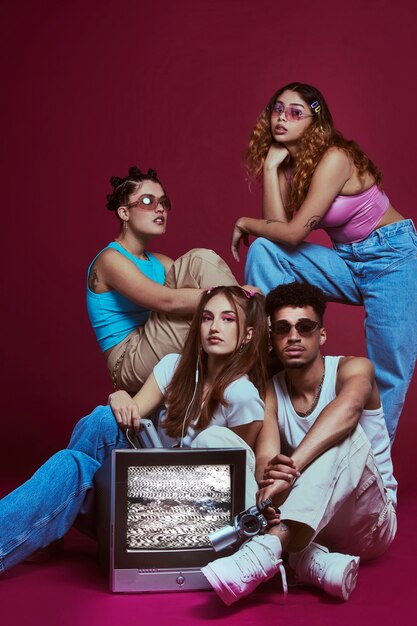 Retrato de jovens amigos no estilo de moda dos anos 2000 posando com tv