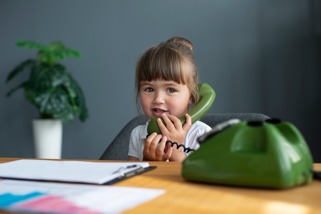 Retrato de linda garota falando no telefone giratório no escritório