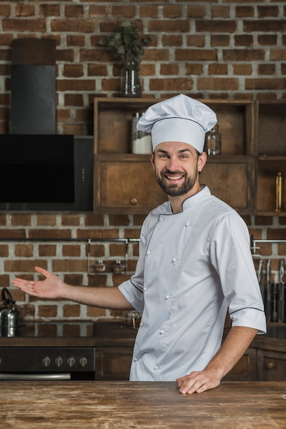 Foto grátis retrato, de, macho, cozinheiro, ficar, em, a, cozinha, apresentando