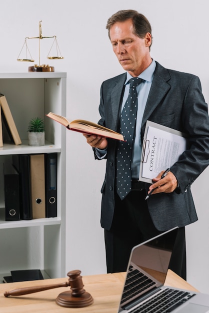 Retrato, de, macho maduro, advogado, segurando, contrato, documento, e, caneta, livro leitura