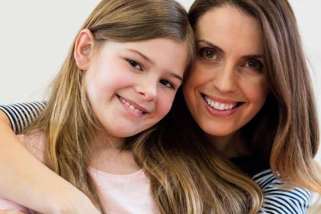 Retrato de mãe e filha que abraçam-se no r de estar