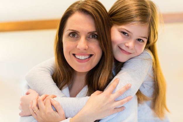 Retrato de mãe e filha que abraçam-se