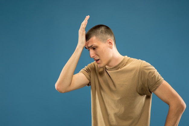 Retrato de meio comprimento de jovem caucasiano no espaço azul. lindo modelo masculino em camisa