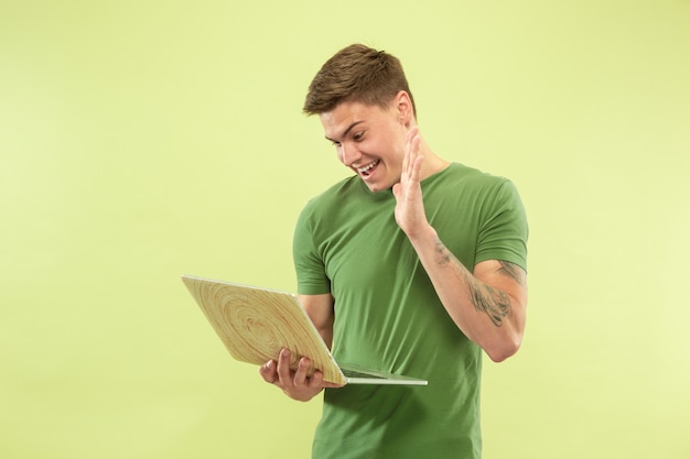 Foto grátis retrato de meio comprimento de jovem caucasiano no espaço verde do estúdio. lindo modelo masculino em camisa