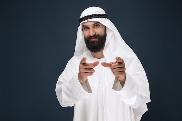 Foto grátis retrato de meio corpo do empresário saudita árabe em estúdio azul escuro