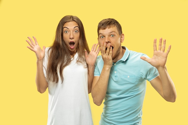 Retrato de meio corpo do lindo casal jovem. Mulher e homem em camisas chocados, pasmos, surpresos e atônitos. Expressão facial, conceito de emoções humanas. Cores da moda.