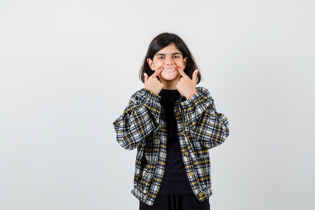 Retrato de menina adolescente abrindo a boca com os dedos em uma camisa casual e olhando alegre para a frente