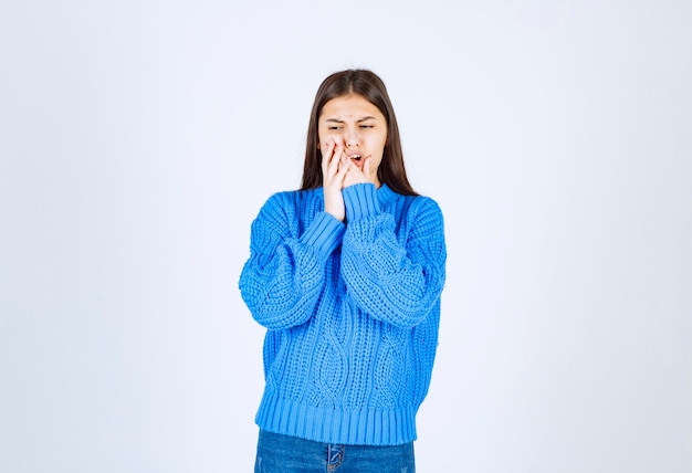 Retrato de menina adolescente em suéter azul tendo dor de dente em branco.