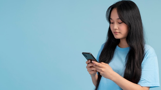 Retrato de menina adolescente verificando o telefone com espaço de cópia