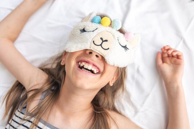 Retrato de menina adorável subiu em sua cama na manhã ensolarada