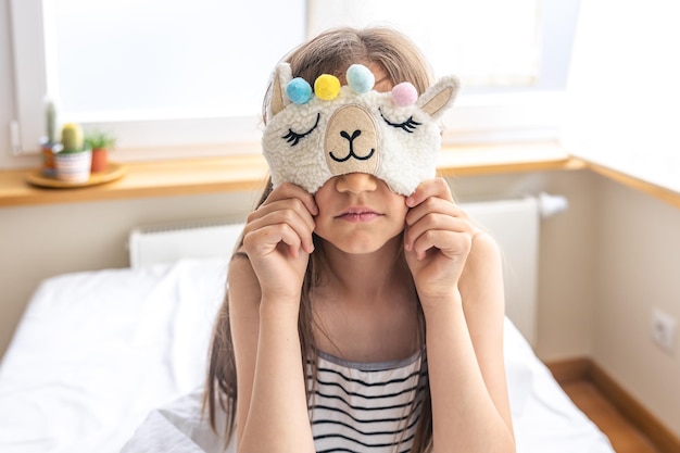 Retrato de menina adorável subiu em sua cama na manhã ensolarada