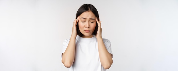 Foto grátis retrato de menina asiática sentindo enxaqueca de dor de cabeça ou estando doente em camiseta branca sobre fundo branco