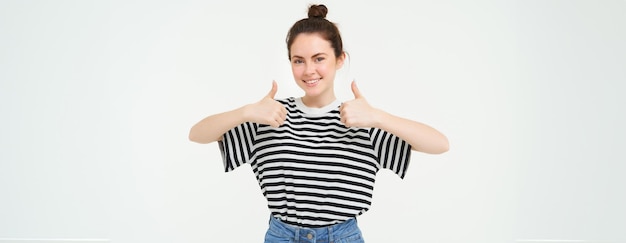 Foto grátis retrato de menina bonita estudante mostra polegares para cima recomenda produto aprova escolha gosta item está