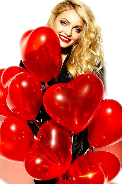 retrato de menina bonita feliz sorridente mulher loira doce segurando nas mãos balões de coração vermelho em roupas casual preto hipster