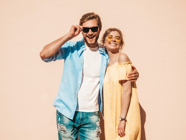 Retrato de menina bonita sorridente e seu namorado bonito. Mulher de vestido casual de verão e homem de jeans. Família feliz e alegre. Fêmea se divertindo na rua perto da parede