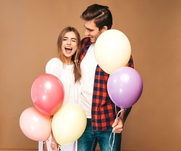 Retrato de menina bonita sorridente e seu namorado bonito segurando o monte de balões coloridos e rindo. Casal feliz no amor. feliz Aniversário