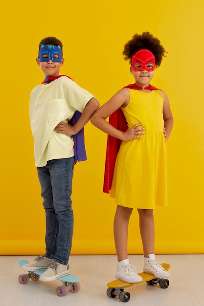 Retrato de menina e menino com capas de super-heróis em skates