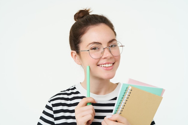 Retrato de menina inteligente com óculos tutor segurando caneta e caderno aluno carregando suas anotações de lição de casa
