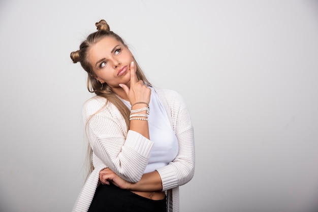 Foto grátis retrato de menina pensativa, olhando para cima e segurando a mão no queixo.