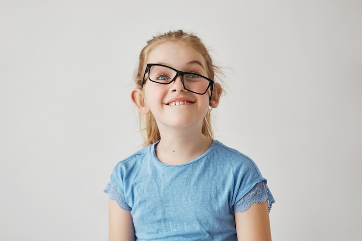 Foto grátis retrato de menina pequena engraçado com olhos azuis e cabelos claros na camisa azul se divertindo com os óculos do pai. conceito de infância feliz.