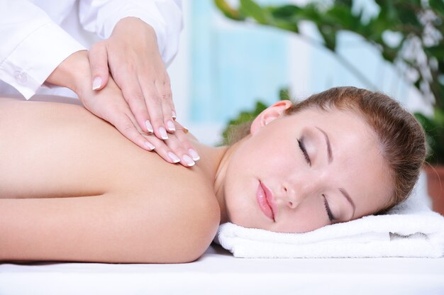 Retrato de menina recebendo massagem e relaxamento nas costas no salão spa