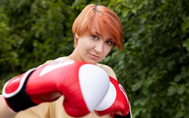 Retrato de menina ruiva confiante com luvas de boxe