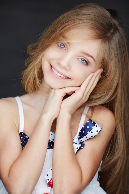 Retrato de menina sorridente em um vestido com cabelo comprido. Isolado em cinza