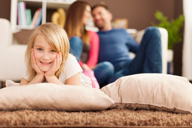 Retrato de menina sorridente relaxando no tapete da sala de estar