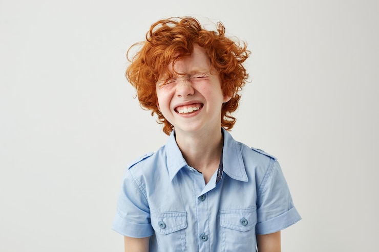 Foto grátis retrato de menino alegre com cabelos ruivos e sardas rindo alto com os olhos fechados