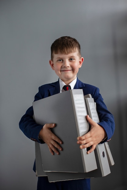 Retrato de menino bonito vestindo terno e segurando arquivos de escritório
