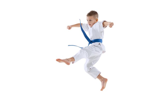 Retrato de menino de quimono com treinamento de faixa azul isolado sobre fundo de estúdio branco