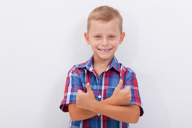 Retrato de menino feliz, mostrando os polegares para cima gesto